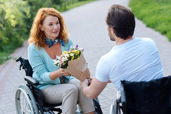 Niza sénior en silla de ruedas mujer recibiendo un ramo de flores — Foto de Stock