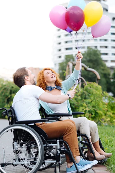 Alegre pareja discapacitada senior sosteniendo globos —  Fotos de Stock