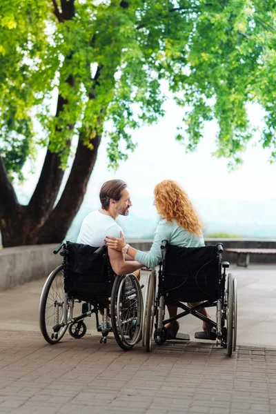 Rear view of a nice disabled couple resting in the park