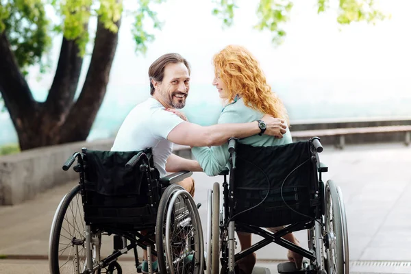 Aardige wheelchaired man rust met zijn vrouw in het park — Stockfoto