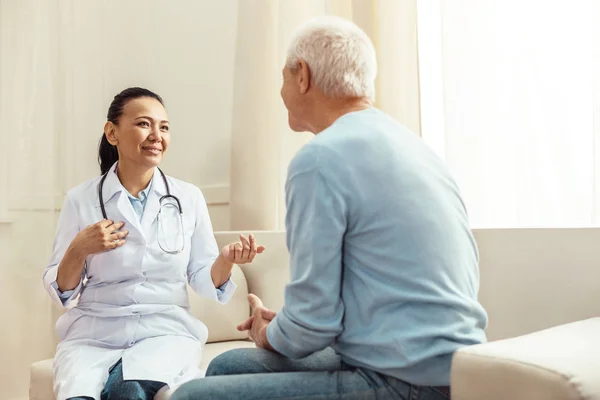 Задоволена позитивна медсестра розмовляє зі своїм пацієнтом — стокове фото