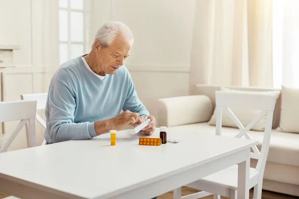 Simpatico uomo anziano in possesso di una scatola con pillole — Foto Stock
