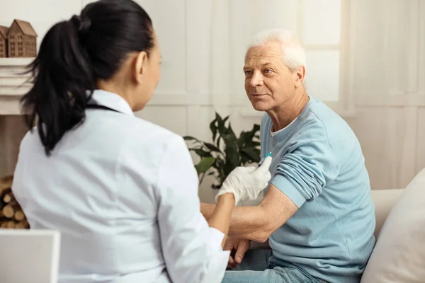 Joyful aged man looking at his nurse