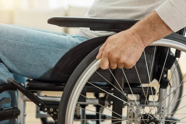Ευχάριστη ηλικιωμένος άνδρας κρατώντας ένα τροχό με αναπηρικό καροτσάκι — Φωτογραφία Αρχείου