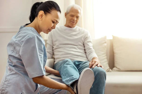 Deliziata infermiera piacevole guardando i suoi pazienti gamba — Foto Stock