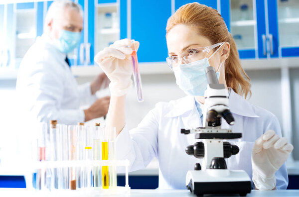 Serious researcher watching pink liquid