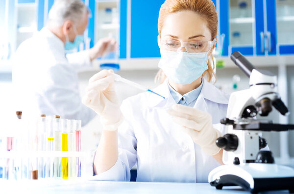 Attentive lab assistant pouring some drops