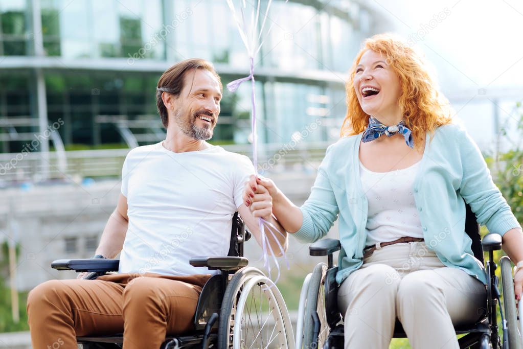 Joyful senior wheelchaired couple enjoying walk in the park