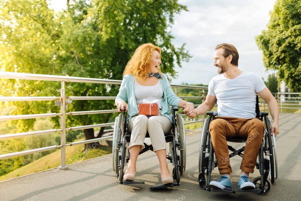 Emotional senior couple resting outdoors in the wheelchairs