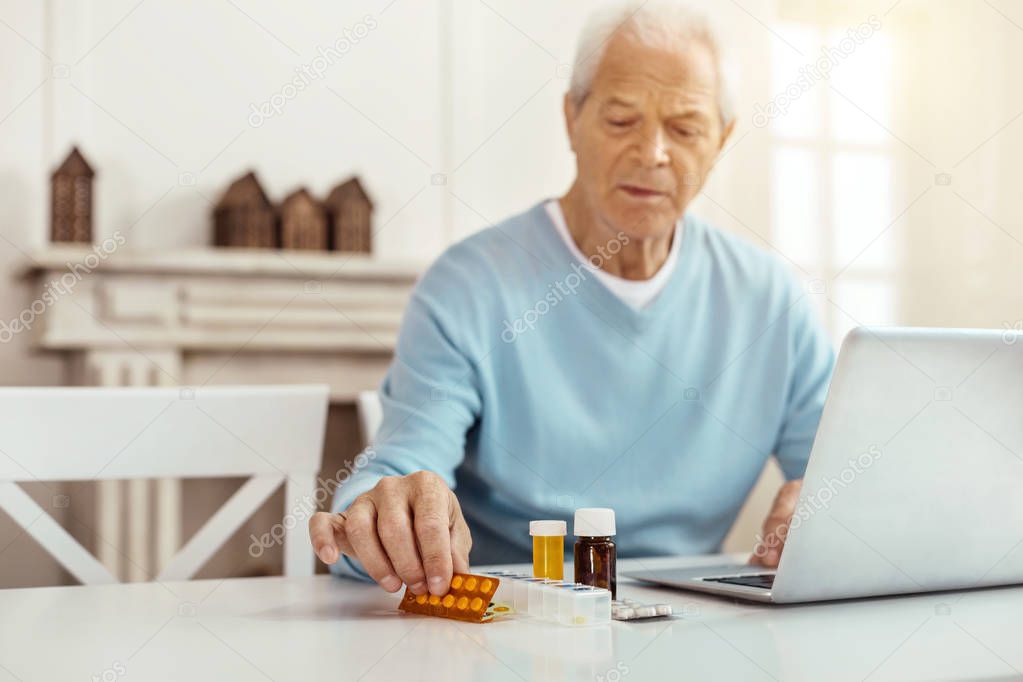 Cheerless aged man taking a blister pack
