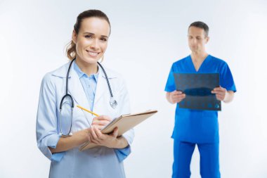 Kameraya gülümseyen defter ile neşeli doktor