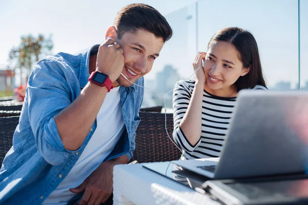 Young boyfriend and girlfriend sharing earphones outdoors — Stock Photo, Image