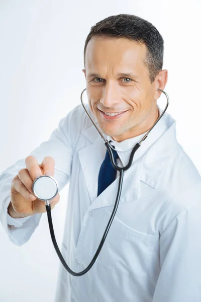 Pratico sorridente in posa con stetoscopio per fotocamera — Foto Stock