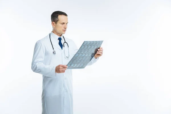 Сосредоточенный практикующий смотрит на МРТ-изображение тела пациента — стоковое фото