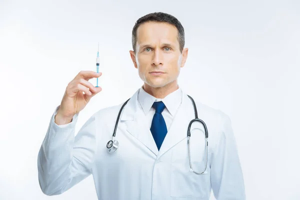 Serious practitioner holding syringe over background — Stock Photo, Image