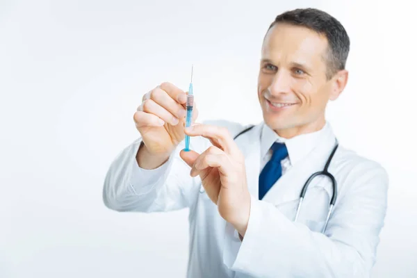 Promienna dojrzałe lekarz ogląda strzykawki — Zdjęcie stockowe