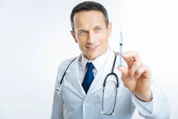 Satisfied doctor checking syringe before injection — Stock Photo, Image