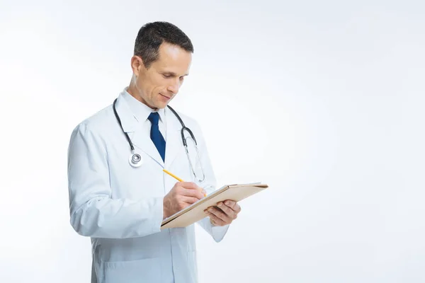 Médico masculino de casaco branco fazendo anotações sobre fundo — Fotografia de Stock
