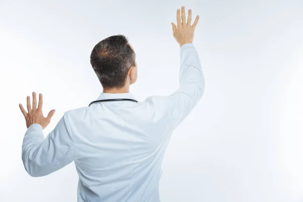 Turned back doctor holding hands on invisible screen — Stock Photo, Image