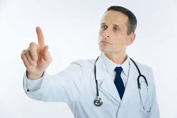 Serious mature doctor using invisible touchscreen alone — Stock Photo, Image