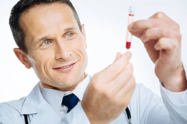 Primo piano del medico allegro che guarda la provetta — Foto Stock