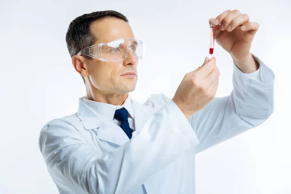 Médico intelectual olhando para tubo de teste com amostra de sangue — Fotografia de Stock