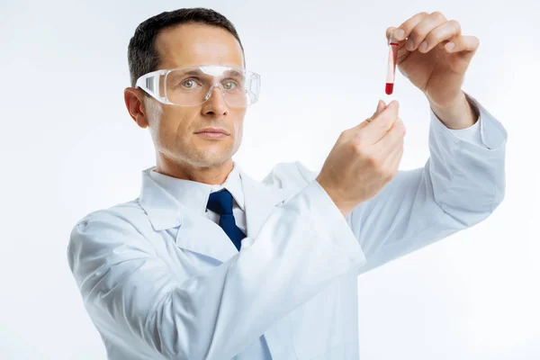 Cientista médico sério com amostra de sangue olhando para a câmera — Fotografia de Stock