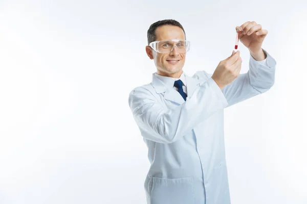 Radiant doctor looking at glass tube with blood sample — Stock Photo, Image