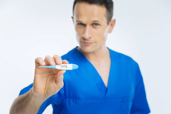 Handsome doctor showing thermometer into camera — Stock Photo, Image