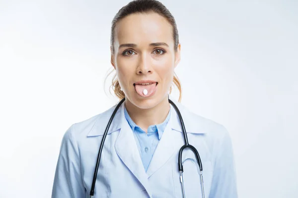 Hazel eyed dokter pil houden op haar tong — Stockfoto