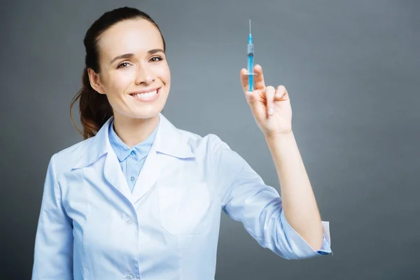 Fröhlicher Mediziner posiert mit Spritze — Stockfoto