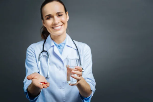 Mindful female doctor brining pills and water — Stock Photo, Image