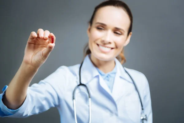 Beaming female doctor looking at pill — Stock Photo, Image