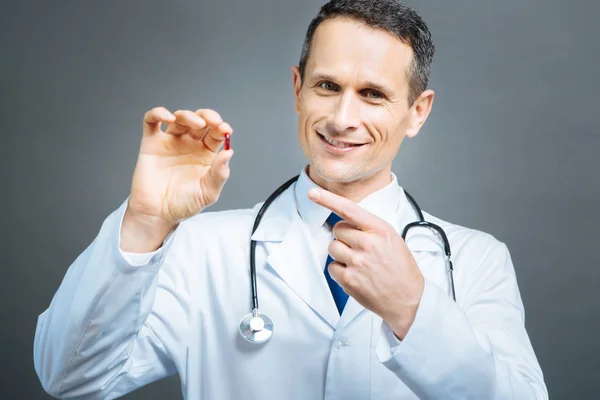 Medico maturo mostrando vitamina rossa — Foto Stock