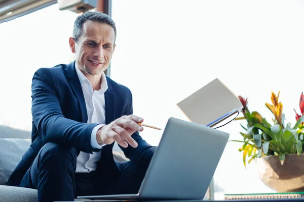 Alegre empresario agradable apuntando a la pantalla del ordenador portátil — Foto de Stock