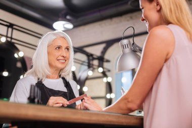 Çivi yaparken onun istemcide gülümseyen kıdemli manikürcü