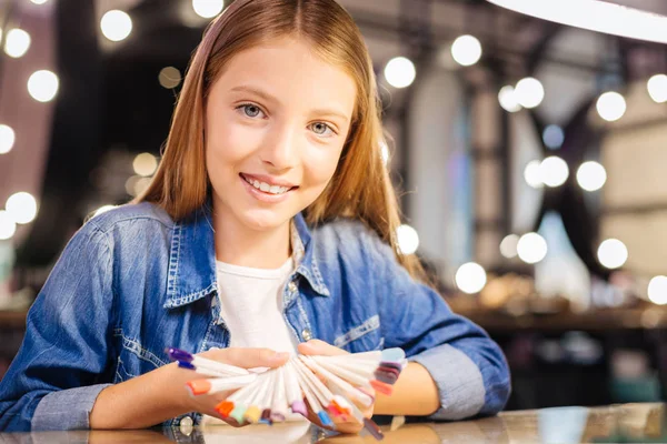 Pleasant girl holding a nail polish color palette and smiling — Stock Photo, Image