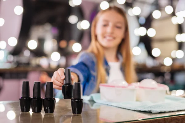 Smiling teenage girl picking nail polish — Stock Photo, Image