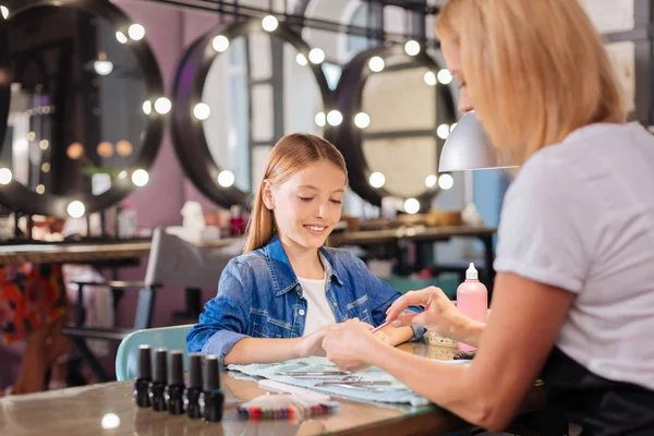 Sevimli genç manikürcü çivi genç istemcisinin dosyalama