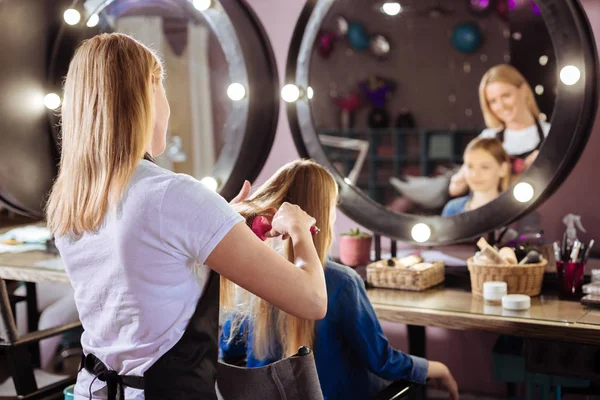 Angenehmer Friseur kämmt die Haare seiner Kundin — Stockfoto