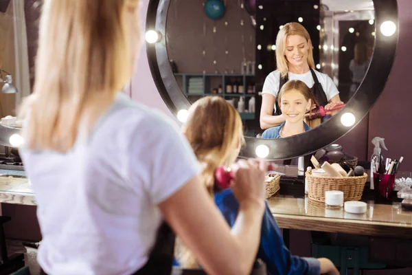 Fille joyeuse se faisant brosser les cheveux dans un salon de beauté — Photo