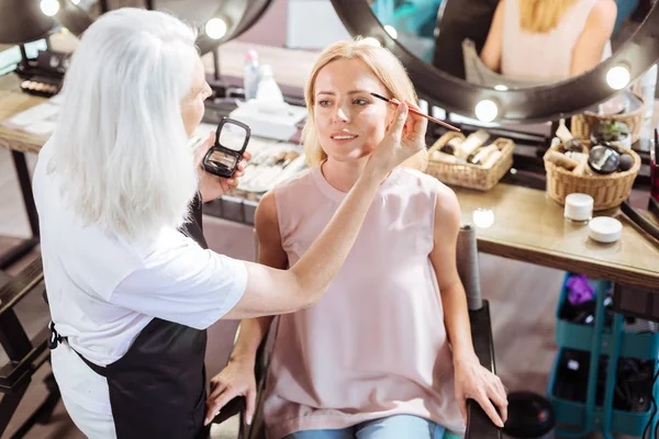 Senior makeup artist applying eyebrow powder — Stock Photo, Image
