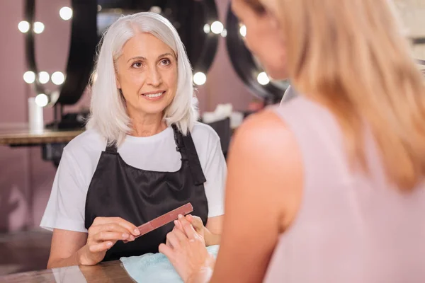 Senior makijażystki, patrząc na jej klient podczas składania paznokcie — Zdjęcie stockowe