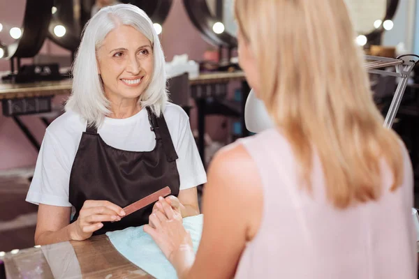 Γοητευτικό μανικιουρίστα χαμογελώντας σε πελάτη της, ενώ η κατάθεση νύχια — Φωτογραφία Αρχείου