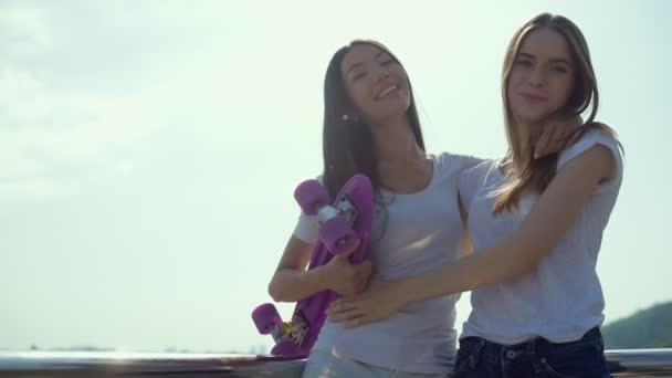 Hübsche Mädchen, die sich auf der Brücke umarmen — Stockvideo