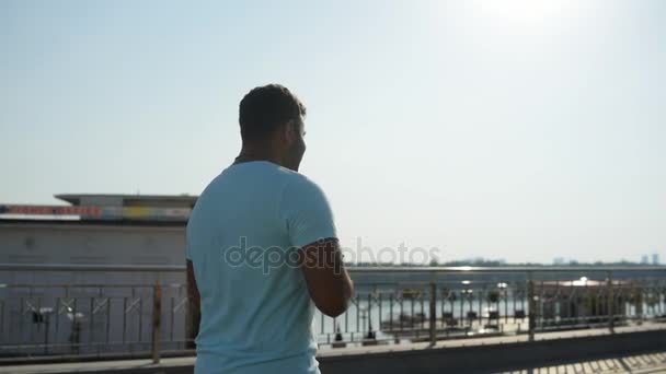 Vista trasera del hombre indio sonriente usando teléfono móvil y caminando afuera — Vídeos de Stock