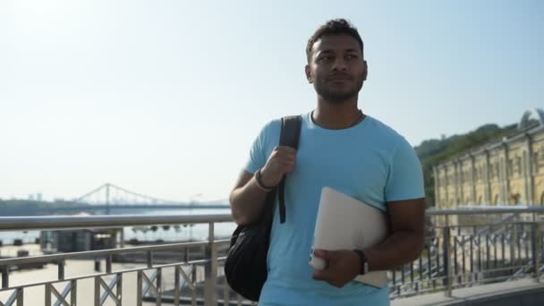 Hombre reflexivo caminando con el portátil y la mochila — Vídeo de stock