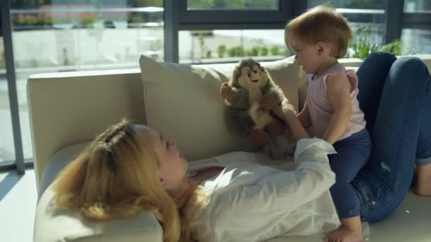 Улыбающаяся мать поднимает ребенка на диван — стоковое видео