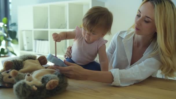 Улыбающаяся мать играет в новую игру с маленькой девочкой — стоковое видео