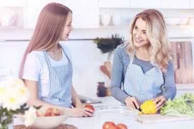 Gülümseyen anne ve kız evde birlikte yemek pişiriyorlar.